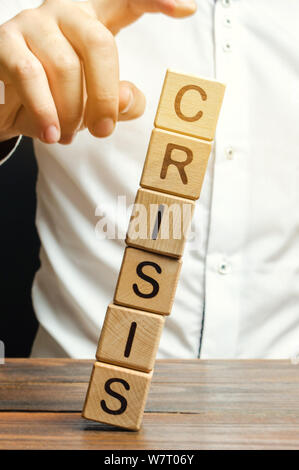 Businessman supprime les blocs en bois avec le terme de crise. La sortie de crise et la stabilité financière. L'accent sur la résolution de la crise de la quarantaine. Le r Banque D'Images