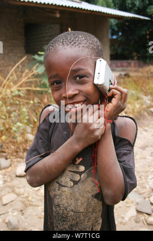 Garçon Malawien à écouter une radio transistor, l'île de Chizumulu, Malawi Banque D'Images