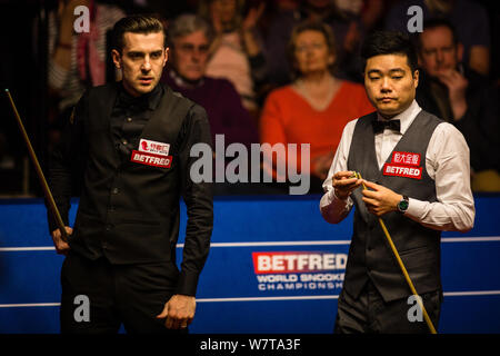 Ding Junhui de Chine, la droite, les craies son cue qu'il estime un tir de Mark Selby, d'Angleterre, dans la dernière phase de leur match de demi-finale au cours de la 2017 Banque D'Images