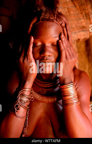 Femme Himba (Otjize appliquer un mélange de beurre, d'ocre et de cendres) à sa peau, Kaokoland, Namibie, septembre 2013. Banque D'Images