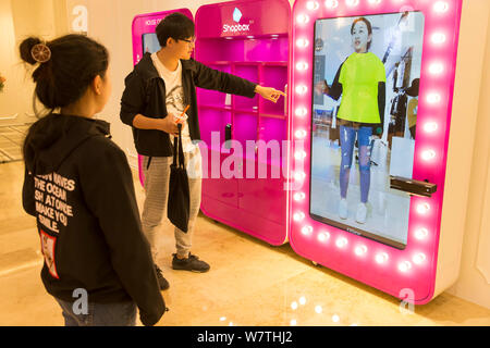 Une femme essaie sur les vêtements à l'aide d'un salon d'essayage virtuel 3D à un centre commercial à Nanjing, Jiangsu province de Chine orientale, le 8 mai 2017. Les consommateurs essayé o Banque D'Images