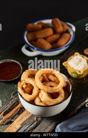 Certains calamares a la romana, Fried squid battues typique de l'Espagne, les anneaux dans un bol blanc et quelques croquettes espagnoles dans une plaque d'émail bleu et blanc Banque D'Images