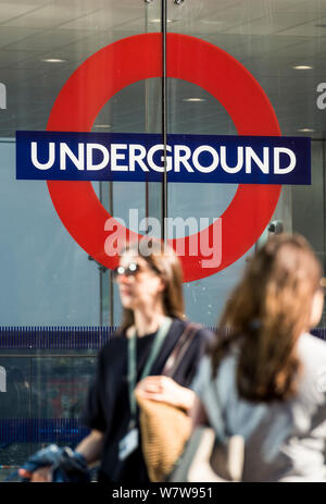 Deux femmes sur leur trajet du matin à l'entrée de la station de métro Victoria, au centre de Londres. Banque D'Images
