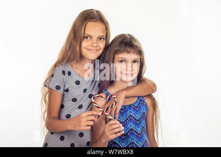 Deux filles hugging a fait un coeur de deux sucettes Banque D'Images