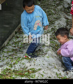 Les enfants jouer avec l'un de la taille d'une pièce de yuan-grêlons sur une route dans la ville de Guiyang, province du Guizhou en Chine du sud-ouest, 6 avril 2017. Les grêlons hi Banque D'Images