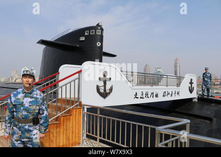 Des soldats de la marine chinoise montent la garde à côté d'un type de sous-marins nucléaires déclassés-091 à l'affiche au Musée de la Marine chinoise dans la ville de Qingdao, à l'est Chi Banque D'Images