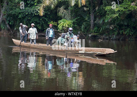 La population locale crossing river en pirogue en bois, y compris l'homme avec des marchandises sur moto, Parc National de la Salonga, Equateur, République démocratique du Congo, mai 2012. Banque D'Images