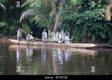 La population locale crossing river en pirogue en bois, y compris l'homme avec des marchandises sur moto, Parc National de la Salonga, Equateur, République démocratique du Congo, mai 2012. Banque D'Images
