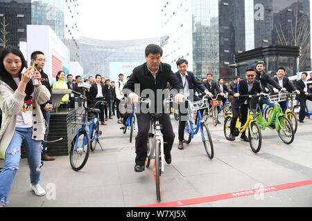 Luo Qiang, avant, maire de Chengdu et d'autres fonctionnaires du gouvernement et les hommes d'affaires chinois de la bicyclette vélo libre-services à l'extérieur un métro sta Banque D'Images