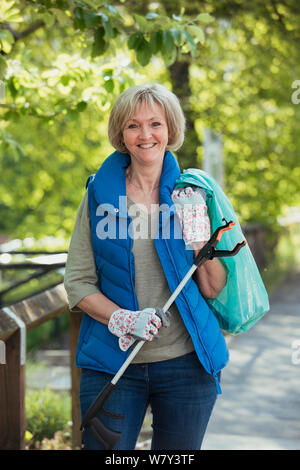 A Portrait of a mature woman standing in a park, participant à une ville propre. Banque D'Images