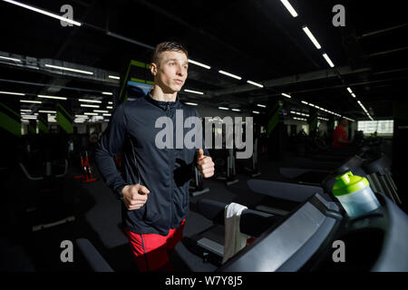 Jogger portant des vêtements d'exécution sur tapis roulant à la salle de sport Banque D'Images