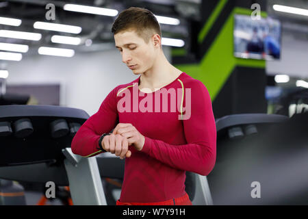 La jeune athlète beau contrôler les résultats sportifs sur smart watch après une bonne session de formation en entraînement fitness gym Banque D'Images