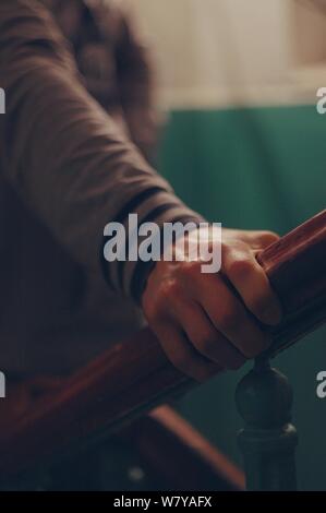 Plan vertical d'une personne tenant la main courante de l'escalier en bois avec un bras serré - ne pas renoncer Banque D'Images
