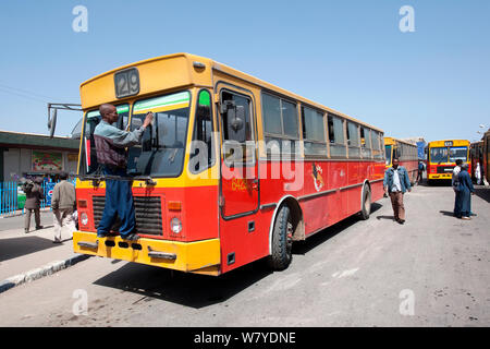 Chauffeur de bus nettoyage du pare-brise du bus à un arrêt de bus à Mercato, Addis Ketema, Addis Ababa, Ethiopie. Février 2009 Banque D'Images