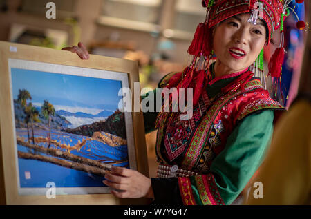 (190807) -- d'HOTEL PARTICULIER, 7 août 2019 (Xinhua) -- Zhang Hua affiche sa mosaïque de plumes aux touristes dans le comté d'Hotel Particulier, préfecture autonome Hani-Yi de Honghe, sud-ouest de la province chinoise du Yunnan, 7 août 2019. Né à Longpeng Canton d'Hotel Particulier, Comté de Yi Zhang Hua, groupe ethnique, s'intéresse à la broderie Yi à partir d'un très jeune âge et a commencé à apprendre ce patchwork plume depuis 2009. En 2016, Zhang Hua fonde un studio pour aider les femmes apprennent la broderie et art plumes pour libre. Puis avec l'appui du gouvernement local, elle a organisé une coopérative spécialisée art plume à b Banque D'Images