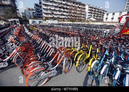 --FILE--vélos de vélo-partage des services chinois Mobike (orange), ofo (jaune) et Xiaoming Danche, ou Xiaoming Vélo (bleu) sont alignés dans un parking gratuit Banque D'Images