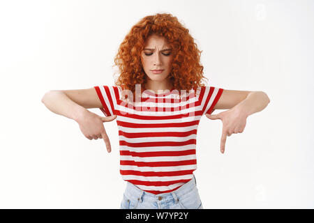 Contrarié déçu young attractive woman européenne rousse frisée rouge d'été T-shirt à rayures froncer se plaindre regarder vers le bas triste cringi Banque D'Images