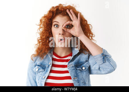 Surprise, d'émotions concept. Surpris belle Rousse aux cheveux bouclés et aux yeux bleus regardant étudiante se demande tenir bon ok sign œil thr Banque D'Images