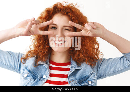 Lucky optimistes caucasian ginger amie curly hairstyle montrer optimiste ludique look disco signe la victoire de la paix près de geste yeux clignant de sassy smilin Banque D'Images