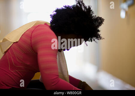 Mid-adult woman assis sur un banc, dans une salle de sport. Banque D'Images