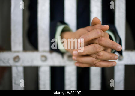 Les mains d'un jeune homme d'adultes à travers les barreaux d'une cellule de prison dans un bâtiment abandonné. Banque D'Images