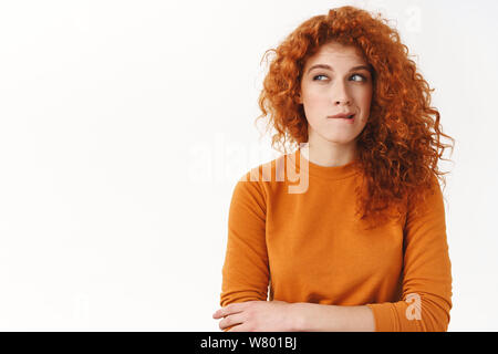 Femme ayant quelque chose d'intéressant sur l'esprit. Creative Smart coupe curly rousse au lèvre piqueurs, louchant réfléchie comme à la pensée de côté, maki Banque D'Images