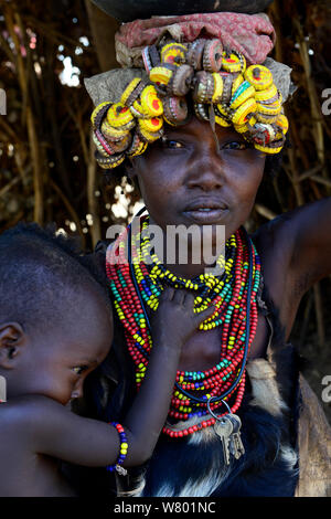 Femme avec enfant, Dassanech en vêtements traditionnels, avec coiffe faite de bottlecaps, vallée de l'Omo. L'Éthiopie, Novembre 2014 Banque D'Images