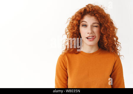 Mignonne rousse espiègle élégant aux cheveux bouclés étudiante à profiter de la vie, le plomb de vie actif, montrant la langue et wink joyeusement, rester positif, un imbécile Banque D'Images