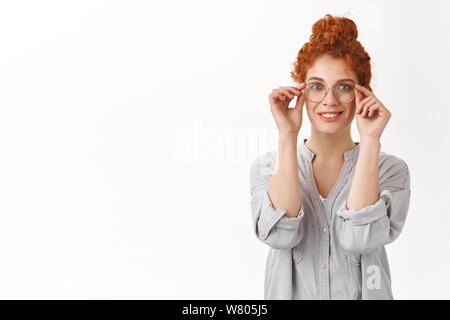 Moderne et charmant mignon Rousse aux cheveux bouclés Woman picking nouvelles lunettes à stocker, souriant heureux trouvé excellent choix, appuyez sur le visage, lunettes grin appr Banque D'Images