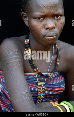 Jeune femme de la tribu Toposas affichage et la peau du visage et du bras de scarification sur les bijoux traditionnels, vallée de l'Omo, en Ethiopie, en mars 2015. Banque D'Images