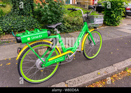 Une lime-E électrique vélo garé dans une rue de banlieue. Banque D'Images