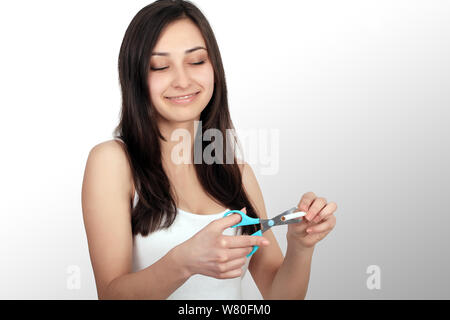 Portrait Of Beautiful Smiling Woman Holding Cigarette et des ciseaux dans les mains. Arrêter de fumer la cigarette Concept. La haute résolution Banque D'Images