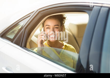 Afro girl talking on phone, sitting in car Banque D'Images