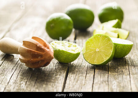 Presse-agrumes en bois et vert lime sur table en bois. Banque D'Images