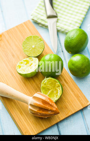 Presse-agrumes en bois et vert lime on cutting board Banque D'Images