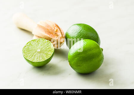 Presse-agrumes en bois et vert lime sur table de cuisine. Banque D'Images