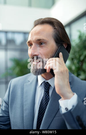 Homme barbu portant veste gris appelant son partenaire d'affaires Banque D'Images