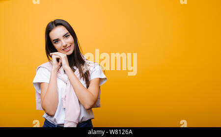 Charming young caucasian woman leaning sa main sur ses mains tout en souriant de plus isolé sur fond jaune. Banque D'Images