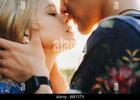 Close up portrait of a cute young caucasian couple blond essayant d'embrasser où l'homme tient sa petite amie dans ses mains face à l'extérieur tout en dat fermer Banque D'Images