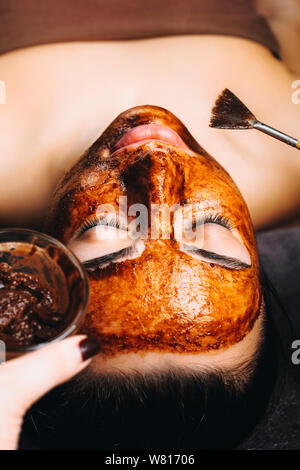 Portrait de femme exceptionnelle appuyée sur un lit spa avec les yeux fermés et avec un chocolat anti age masque sur son visage dans un espace bien-être centre de beauté. Banque D'Images