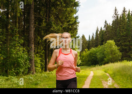 Jeune femme sur un sentier de jogging dans la forêt Banque D'Images