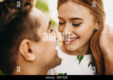 Close up portrait of young couple où red hair girl with freckles essayant d'embrasser son petit ami en souriant toucher ses cheveux roux. Banque D'Images