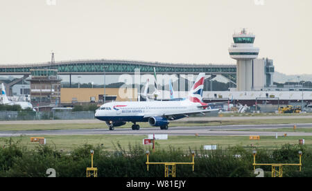 Un British Airways Airbus A320-232 s'éteint la piste en face de la tour de contrôle après l'atterrissage à l'aéroport de Londres Gatwick. Banque D'Images