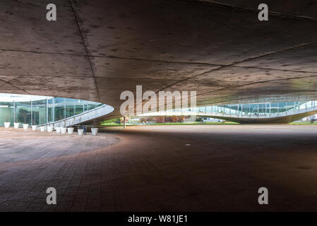 Rez-de-chaussée extérieur de Rolex Learning Center (EPFL) avec fasciner ondulant en béton plancher perforé et le toit avec façade en verre. Banque D'Images