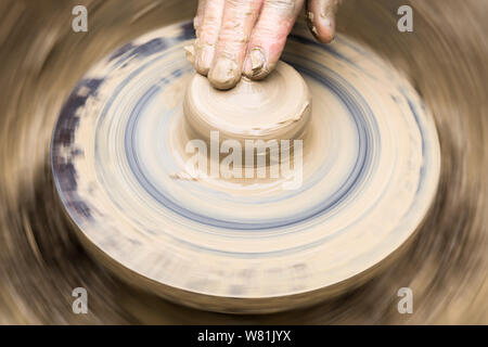 Les doigts de potter toucher la masse informe morceau d'argile sur la roue en rotation Banque D'Images