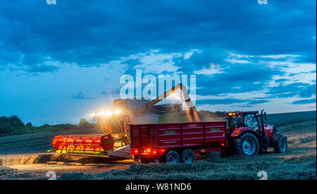 Grantham, Lincolnshire, Royaume-Uni. 7 août 2019. Une pause dans le temps et d'un sèche-linge conditions, après plusieurs jours de pluie, permet aux agriculteurs de travailler tard dans la nuit pour rattraper la combinaison et la récolte avant qu'un autre sort humide de prévision. Crédit : Matt Limb OBE/Alamy Live News Banque D'Images