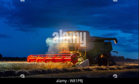 Grantham, Lincolnshire, Royaume-Uni. 7 août 2019. Une pause dans le temps et d'un sèche-linge conditions, après plusieurs jours de pluie, permet aux agriculteurs de travailler tard dans la nuit pour rattraper la combinaison et la récolte avant qu'un autre sort humide de prévision. Crédit : Matt Limb OBE/Alamy Live News Banque D'Images