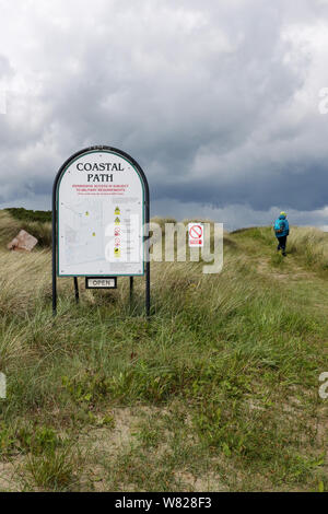 Sentier du littoral signer avec des règles et une femme Walker à l'entrée du chemin côtier Ballykinler en dunes de sable de l'Ballykinler, County Down. Banque D'Images