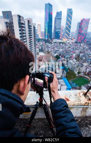 Un chinois prend des photos d'anciennes maisons d'habitation dans village Xicheng Village, qui est en rénovation, entouré d'immeuble de grande hauteur à Guangzhou Banque D'Images