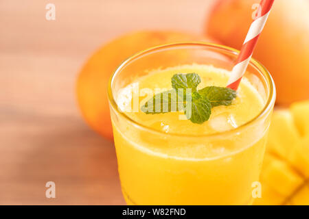 Jus de mangue fraîche avec de belles pâtes chair hachée sur arrière-plan du tableau lumineux en bois. Boisson aux fruits tropicaux concept design. Close up, copiez l'espace. Banque D'Images